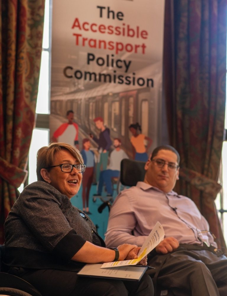 Baroness Tanni Grey-Thompson and Clive Gilbert in front of Accessible Transport Policy Commission poster at the House of Lords